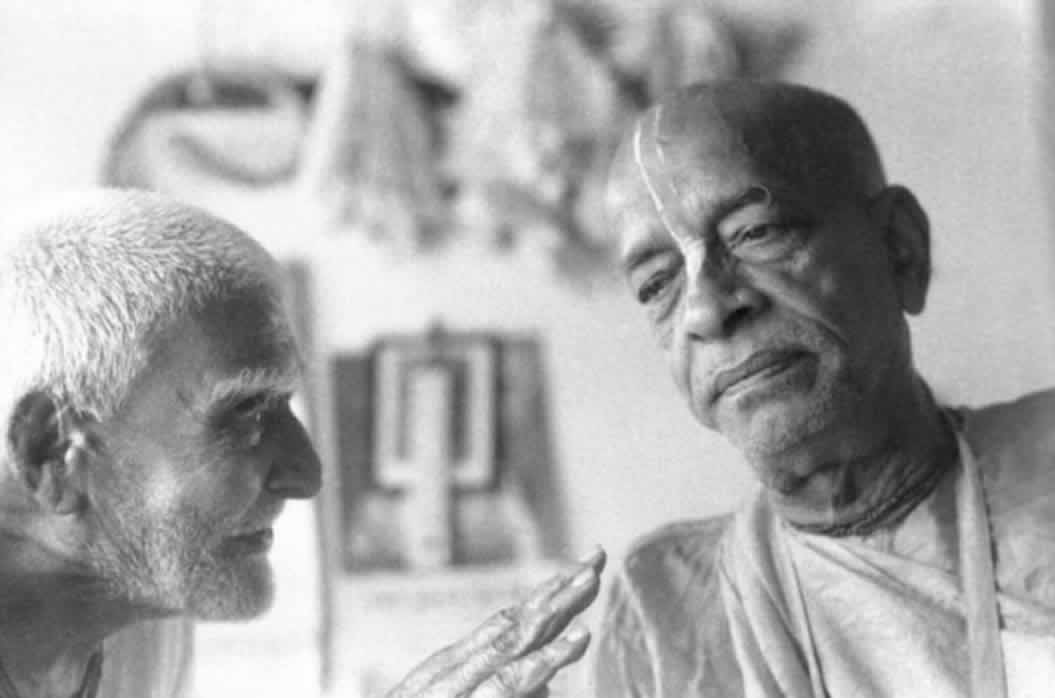 Srila Prabhupada intently listening to a Godbrother tell a story.