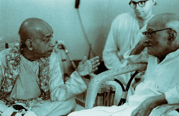 Srila Prabhupada speaking to an elderly gentleman while sitting.